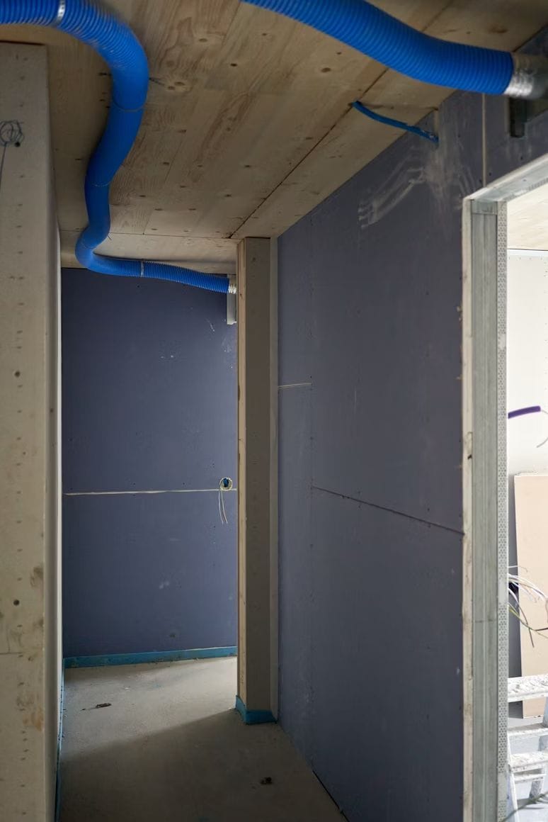 Interior under construction with framing, sheathing and blue ducting overhead